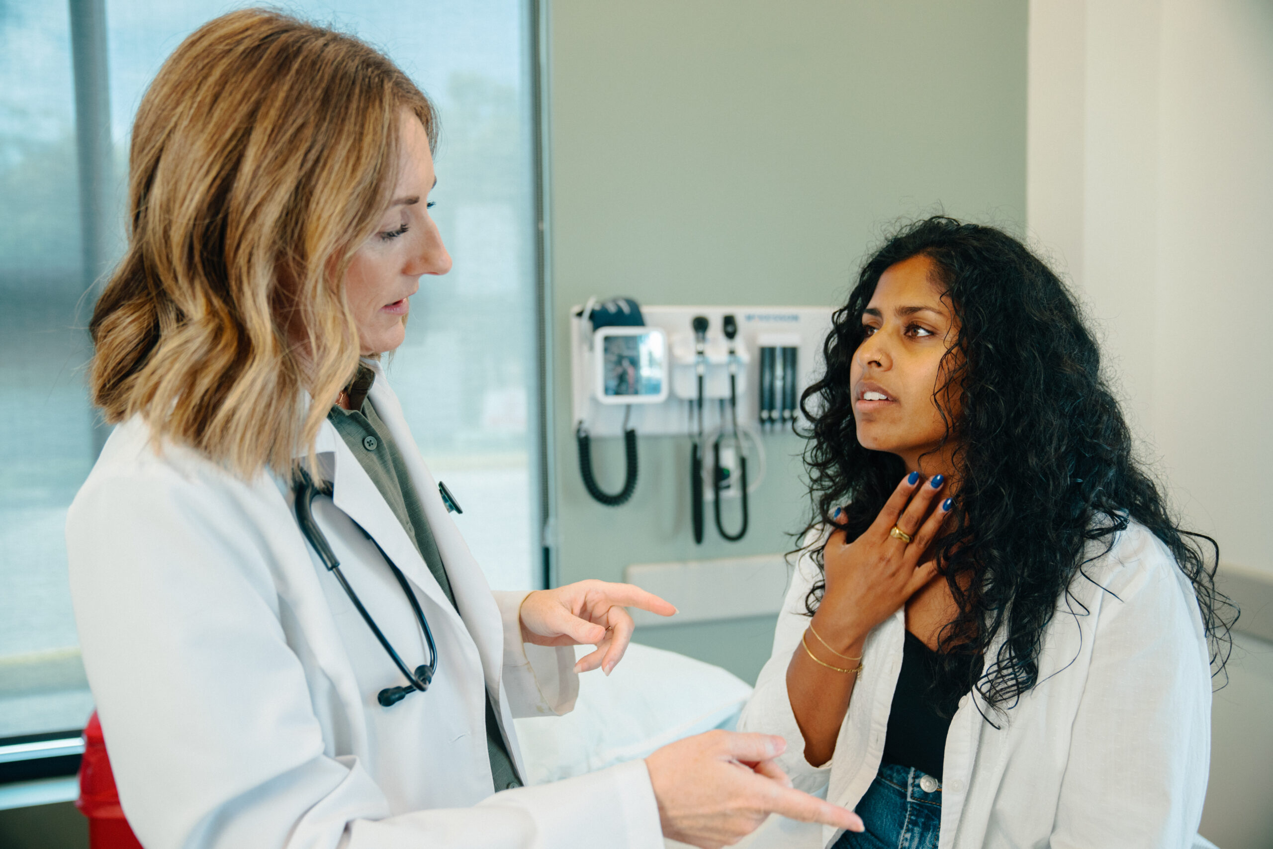 AFC patient touches her neck, describing throat pain, being evaluated for strep throat
